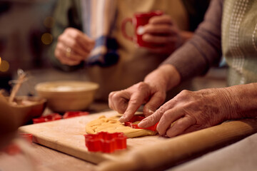 Close up of senior woman using cookie cutter while baking for Christmas.