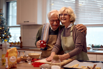 Happy senior couple laughing while baking cookies for Christmas holidays at home.