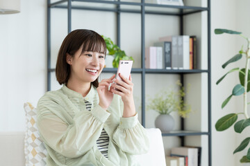 リビングでスマホを使う若い女性
