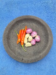 chilies and onions are placed on a pestle with a blue background