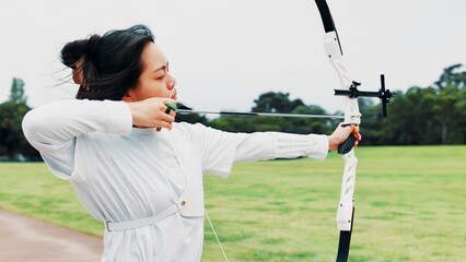 Aim, athlete and woman with bow, challenge and serious for archery, training and equipment for game. Outdoor, skills and talent for sport, shooting and arrow for practice, archer and person in Japan