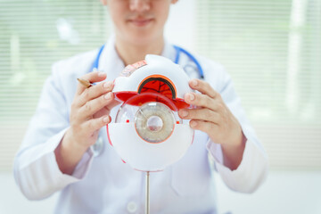 A male doctor wearing glasses sits at a desk in a hospital, explaining eye diseases like glaucoma,...