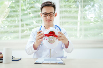 A male doctor wearing glasses sits at a desk in a hospital, explaining eye diseases like glaucoma,...