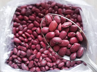 Red beans in a spoon in close-up, with a bag of beans in the background. Cooking of national dishes from legumes. Beans are in the diet. 