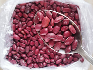 Red beans in a spoon in close-up, with a bag of beans in the background. Cooking of national dishes from legumes. Beans are in the diet. 