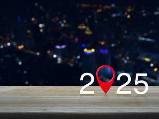 2025 letter with map pin location icon on wooden table over blur colorful night light city tower...