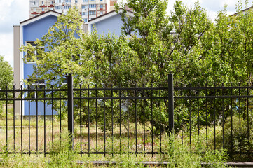 Fototapeta premium Metal fence in the city park. Decorative black iron guardrail for protection, close up