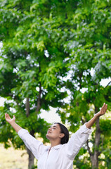 Relaxed happy refreshing young south asian woman taking a deep breath of clean unpolluted air in urban park, good summer, summer wellness, sunlight exposure concept image