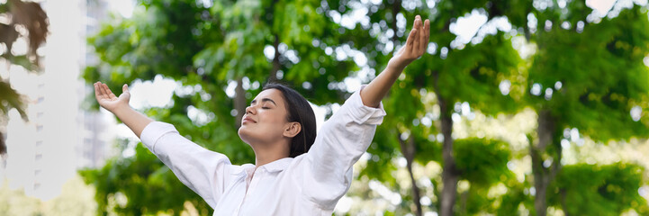 Relaxed happy refreshing young south asian woman taking a deep breath of clean unpolluted air in urban park, good summer, summer wellness, sunlight exposure concept image