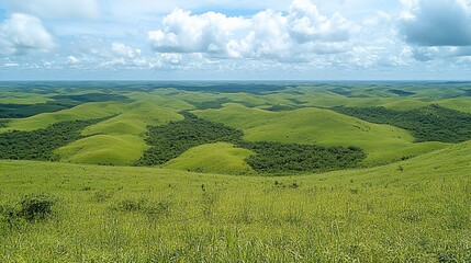 Fototapeta premium Lush green hills under a blue sky with scattered clouds, showcasing a serene landscape.