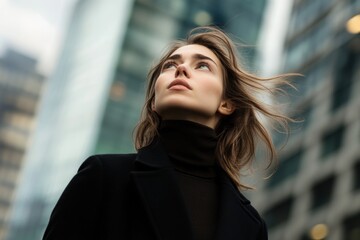 Urban businesswoman confident posture black coat turtleneck sweater wind-blown hair