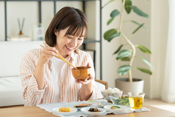 朝食でお味噌汁を飲む若い女性
