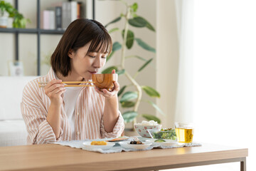 朝食でお味噌汁を飲む若い女性