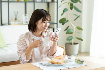 朝食でスマホを見る若い女性