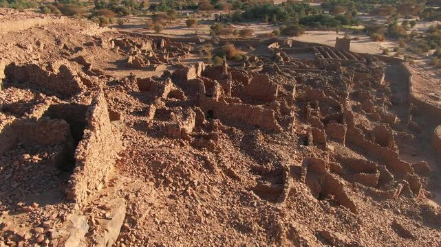 Drone flying over ruins of ancient and historic city of Ouadane, Mauritania in Africa. Aerial forward tilt-up reveal