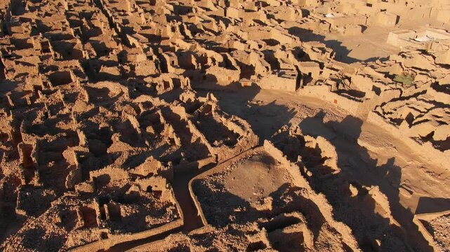Ouadane or Wadan ancient city, ruins, Mauritania in Africa. Aerial backward tilt-up reveal, sky for copy space