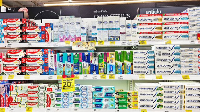 A close-up view of a supermarket shelf stocked with a variety of toothpaste brands and flavors, showcasing a colorful and organized display of oral hygiene products.  Thailand, November 29, 2024