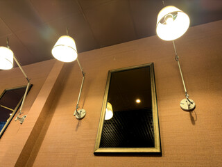 A mirror is hanging on a wall with two lamps above it