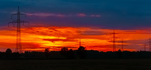 Fototapeta premium Summer sunset with a dramatic sky and overland high voltage lines near Tabertshausen, Deggendorf, Bavaria, Germany