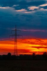 Summer sunset with a dramatic sky and overland high voltage lines near Tabertshausen, Deggendorf, Bavaria, Germany