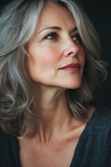 Fototapeta premium Woman with gray hair and a red lipstick is looking at the camera. She has a serious expression on her face
