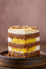 Piece of pumpkin or carrot layered cake with coconut cream, walnut and orange confit in a plate. Sugar, gluten and lactose free. Vegan, healthy dessert. Vertical orientation.