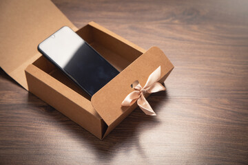 Gift box with a smartphone on the wooden background.