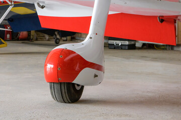 Closeup of wheel of a light single-engine aircraft standing in a hangar