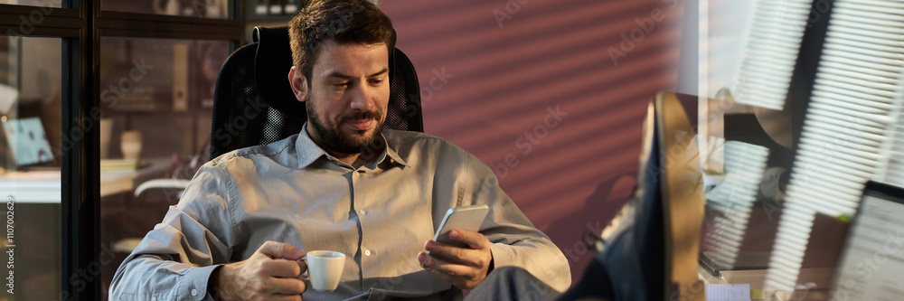 Poster banner of manager with cup of coffee texting in smartphone while sitting in armchair and keeping cro