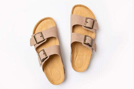 Leather beige sandals birkenstocks on white background top view flat lay. Unisex summer shoes, genuine leather flip flops with cork soles. Stylish fashion footwear, mockup for design