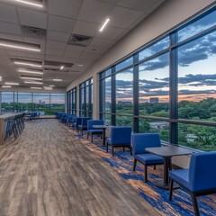 Modern office lounge with large windows offering city views at sunset.