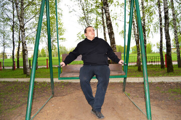 Young autistic guy on a swing in the park