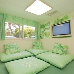 Relaxing tropical themed room with floor cushions, TV, and large window.