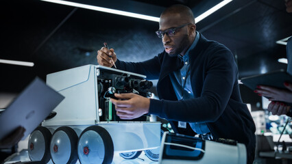African Engineer Using a Screwdriver While Developing a Remotely Controlled Delivery Robot. Black Specialist Working in High Tech Research Laboratory with Modern Equipment