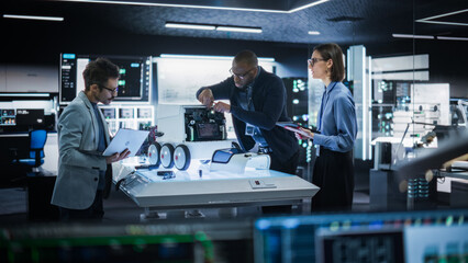 Diverse Team of Industrial Specialists Working on Remotely Controlled Mobility Robot in a Research Facility. Engineers Testing and Fixing Detection Cameras While Using Tablet and Laptop