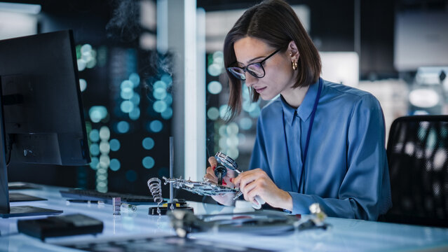 Portrait of Female Specialist Soldering a Circuit Board in a Technologically Advanced Company. Focused Female Engineer Working on a Project, Testing Theory in a Manufacturing Research Facility
