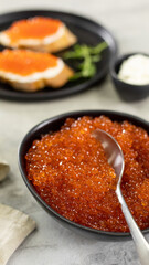 Red caviar in a black plate and sandwiches with caviar
