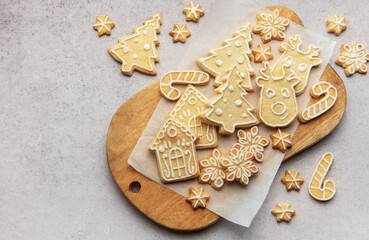 Christmas cookies decorated with icing lying on wooden board