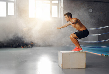A dynamic box jump performed by a fit athlete in a gym, beautifully showcasing their strength and...