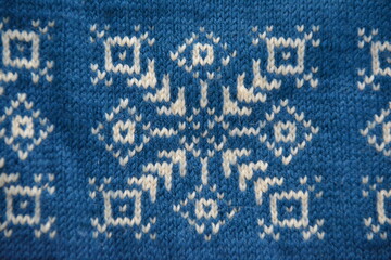 Two-color knitted pattern. White snowflake on blue background.