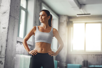A determined woman dressed in a sports bra is showcasing her strength and fitness while in an urban...
