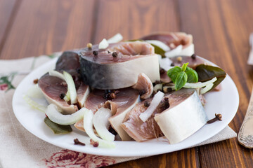 lightly salted mackerel with onions and spices, in a plate on a wooden table
