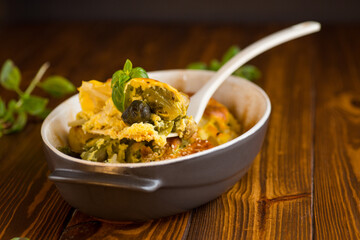 cauliflower and brussels sprouts casserole with cheese, in a ceramic dish on a wooden table