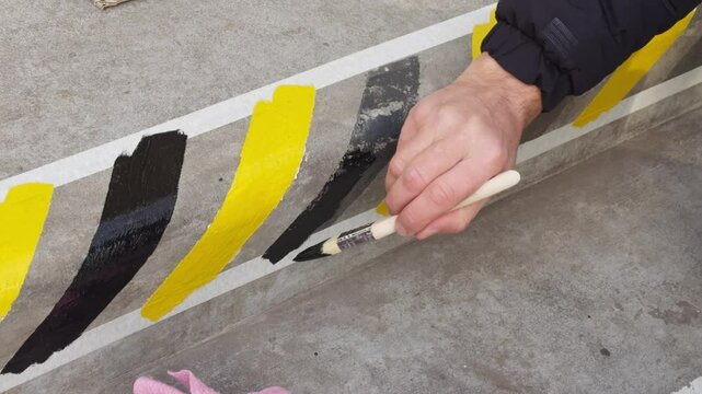 Painting concrete step with black and yellow lines, indicating dangerous height difference.
