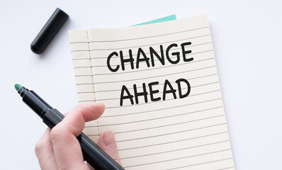 Hand holding marker over notebook with Change AHEAD text. Business concept of satisfaction.