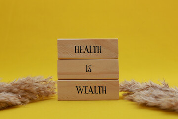 Health is wealth symbol. Yellow cloth background with words Health is Wealth. Beautiful yellow cloth background. Dry flowers on side. Medical and Health and happiness concept. Copy space.