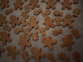 Gingerbread men and comets cookies baking on a tray and paper, ready for the holiday season christmas