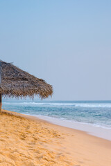 A beach with a big umbrella on the sand