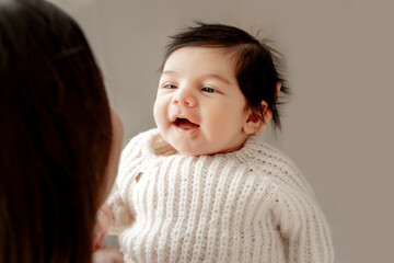 laughing newborn baby in mom's arms on a gray background, place for text, mom holding baby in her arms, close-up portrait, smiling baby