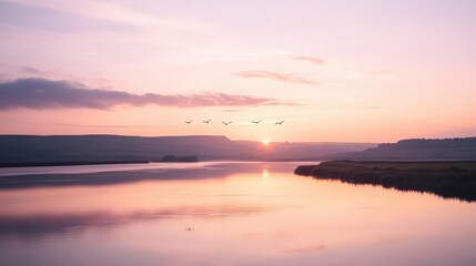 Naklejka premium A calm and tranquil river landscape with the sun setting behind distant hills.
